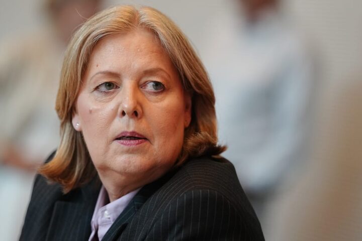 Porträt einer Frau im dunklen Blazer, die zur Seite blickt.