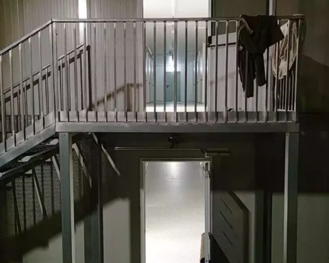 Treppenhaus in einem nüchternen Gebäude mit Metallgeländer und offenen Türen.
