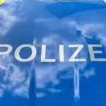 Nahaufnahme der Aufschrift „POLIZEI“ auf einem blauen Polizeifahrzeug.