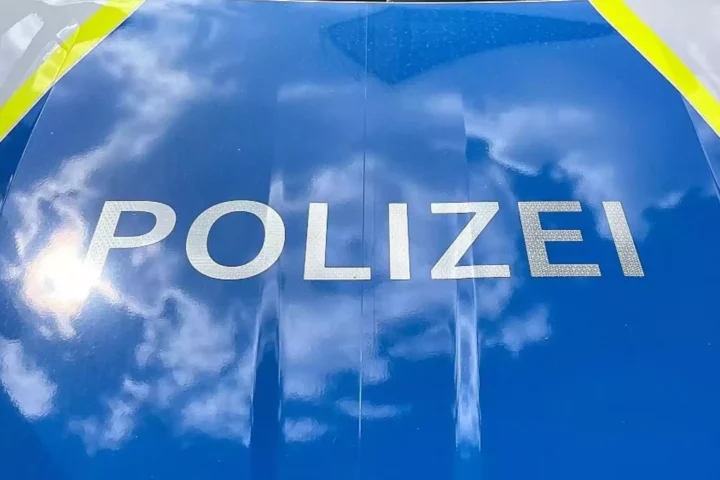 Nahaufnahme der Aufschrift „POLIZEI“ auf einem blauen Polizeifahrzeug.