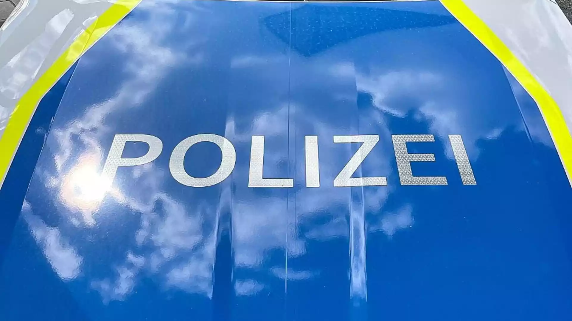 Nahaufnahme der Aufschrift „POLIZEI“ auf einem blauen Polizeifahrzeug.