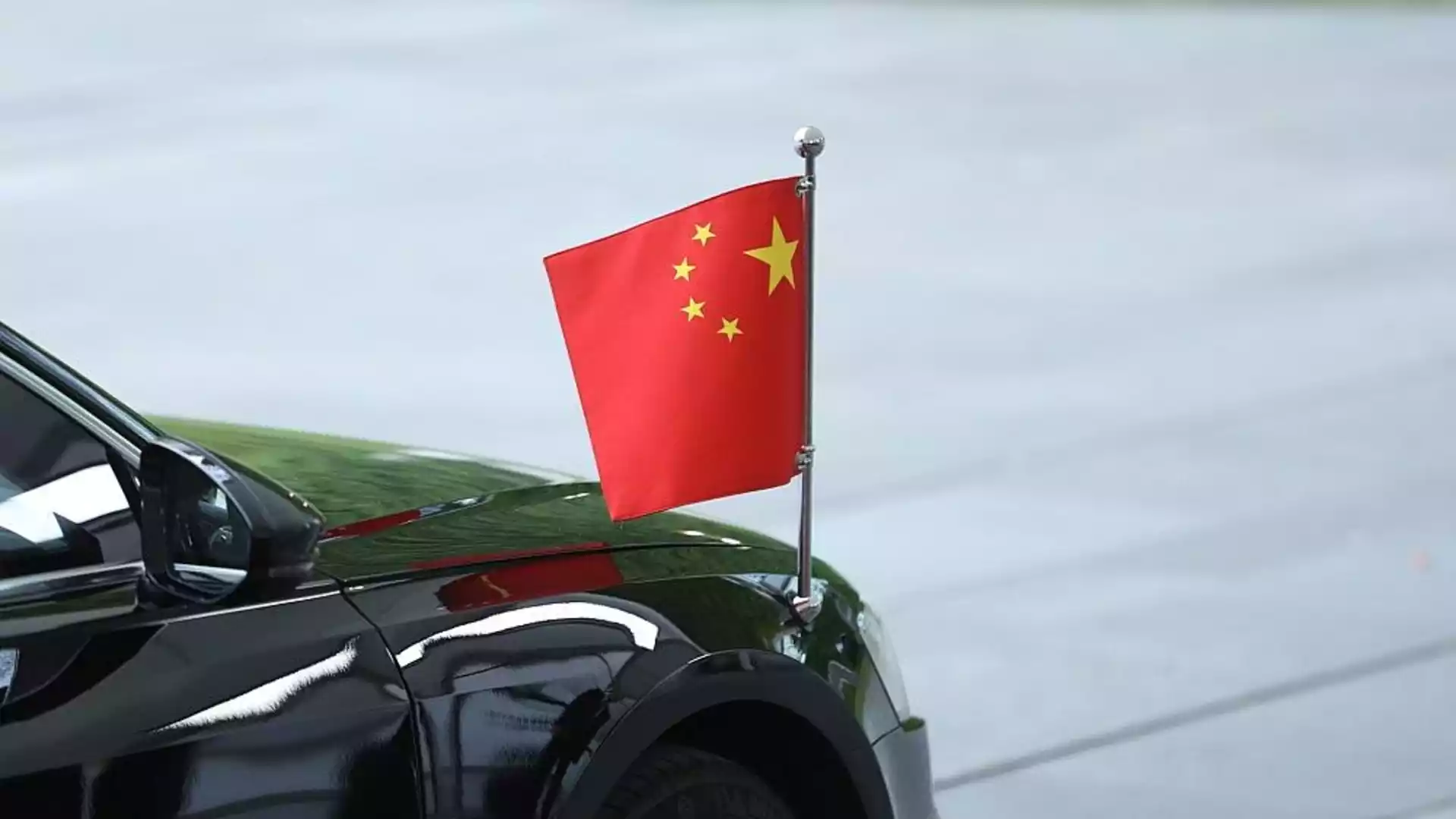 Ein schwarzes Auto mit kleiner chinesischer Flagge auf der Karosserie.
