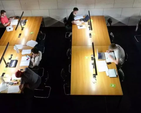 Studierende arbeiten an langen Tischen in einer Lern- oder Bibliotheksumgebung.