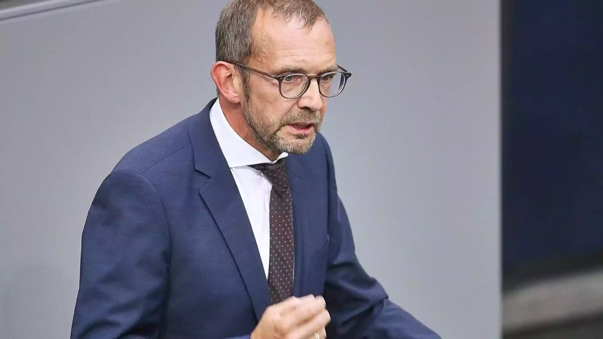 Röwekamp: Unterstützung für Ukraine prägt Europas Sicherheit langfristig 1 Mann im Anzug und mit Brille spricht vor neutralem Hintergrund.