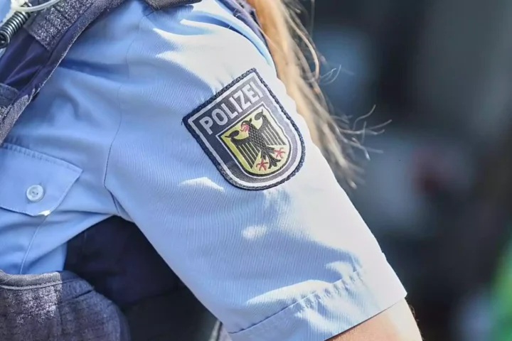 Nahaufnahme des Ärmels einer Polizeiuniform mit Wappen und Schriftzug „Polizei“.