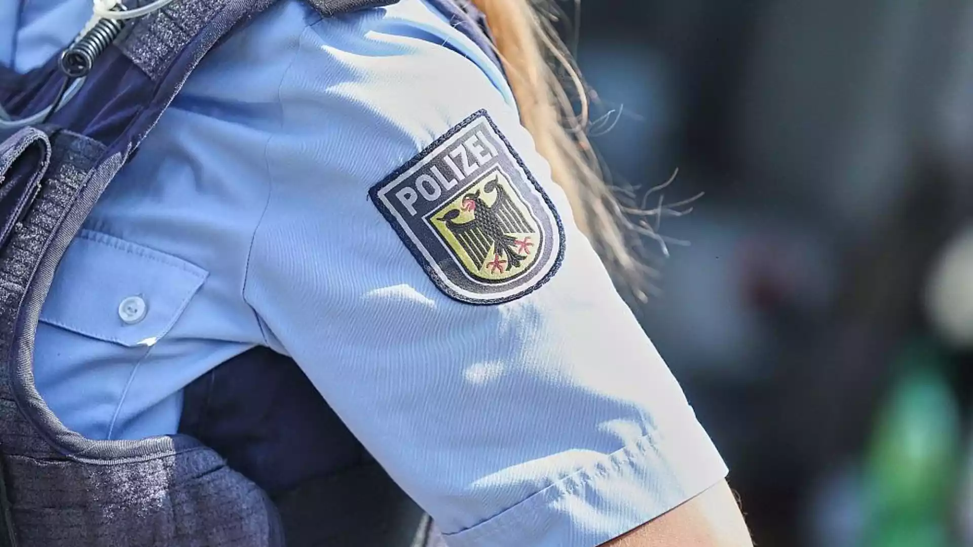 Nahaufnahme des Ärmels einer Polizeiuniform mit Wappen und Schriftzug „Polizei“.