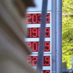 Digitale Kraftstoffpreisanzeige an einer Tankstelle vor grünem Hintergrund.