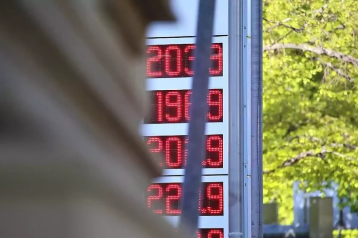 Digitale Kraftstoffpreisanzeige an einer Tankstelle vor grünem Hintergrund.