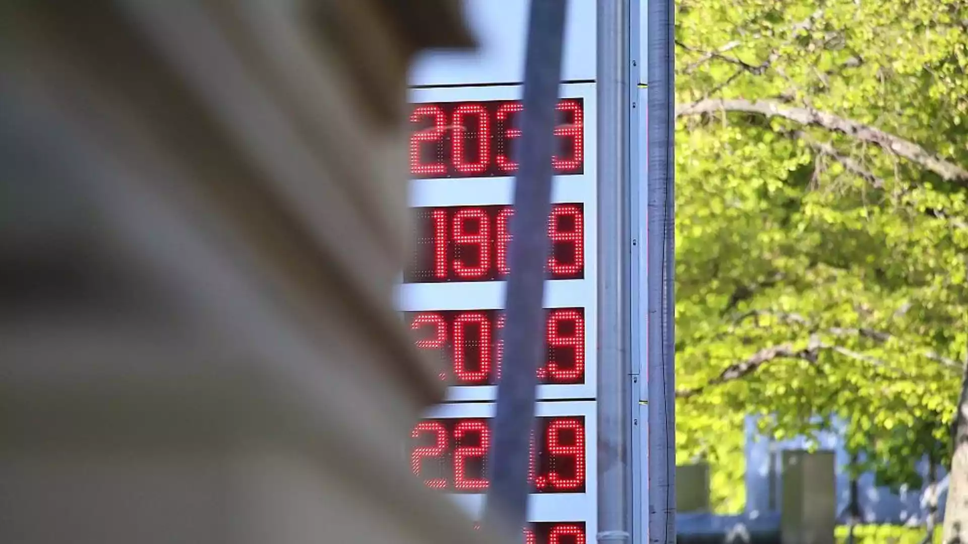 Digitale Kraftstoffpreisanzeige an einer Tankstelle vor grünem Hintergrund.