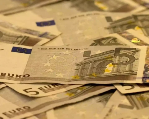 Fünf-Euro-Scheine liegen gestapelt und verstreut auf einer Fläche.