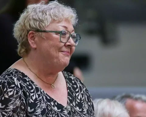 Ältere Frau mit Brille und kurz blondem Haar im Profil.