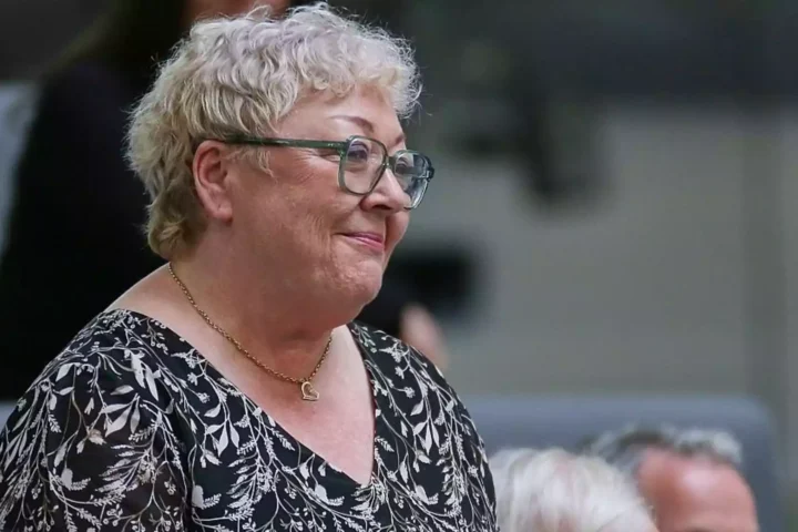 Ältere Frau mit Brille und kurz blondem Haar im Profil.