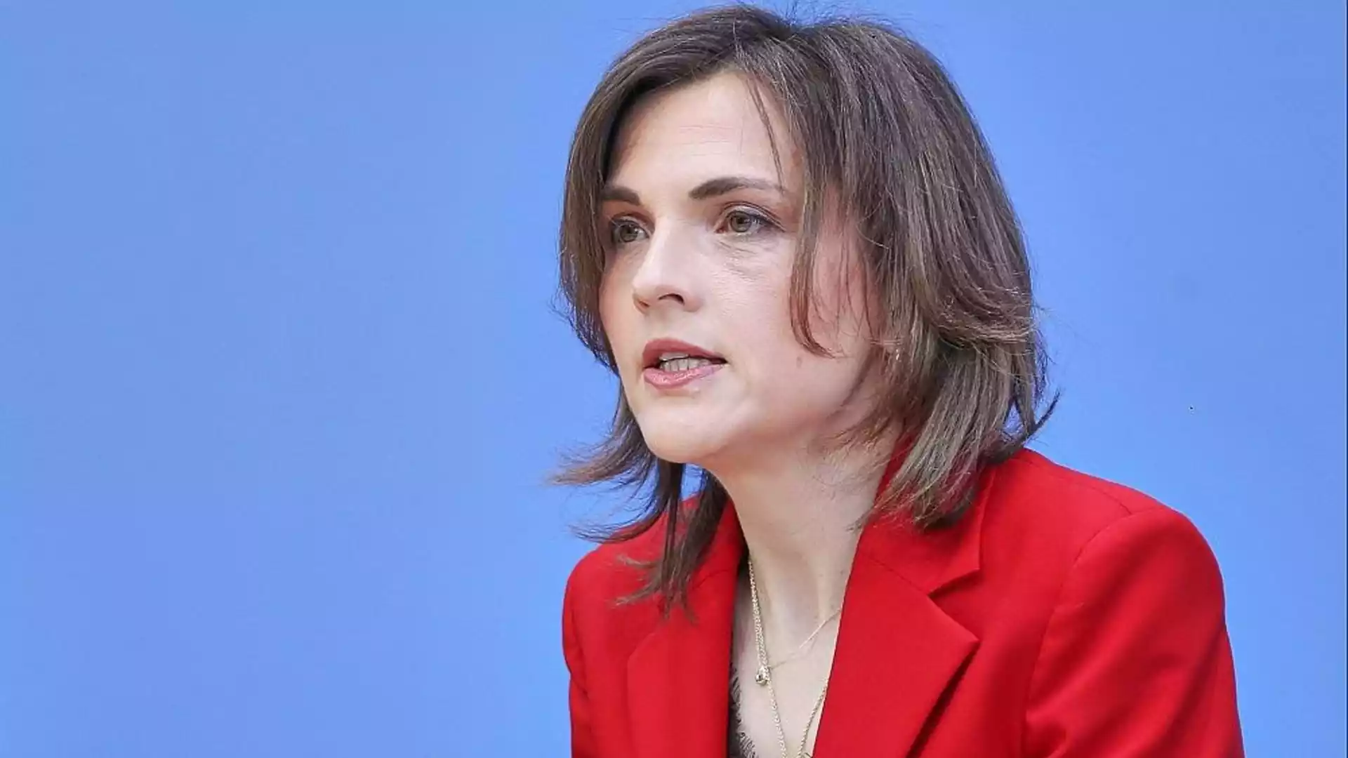 Porträt einer Frau mit rotem Blazer vor blauem Hintergrund.