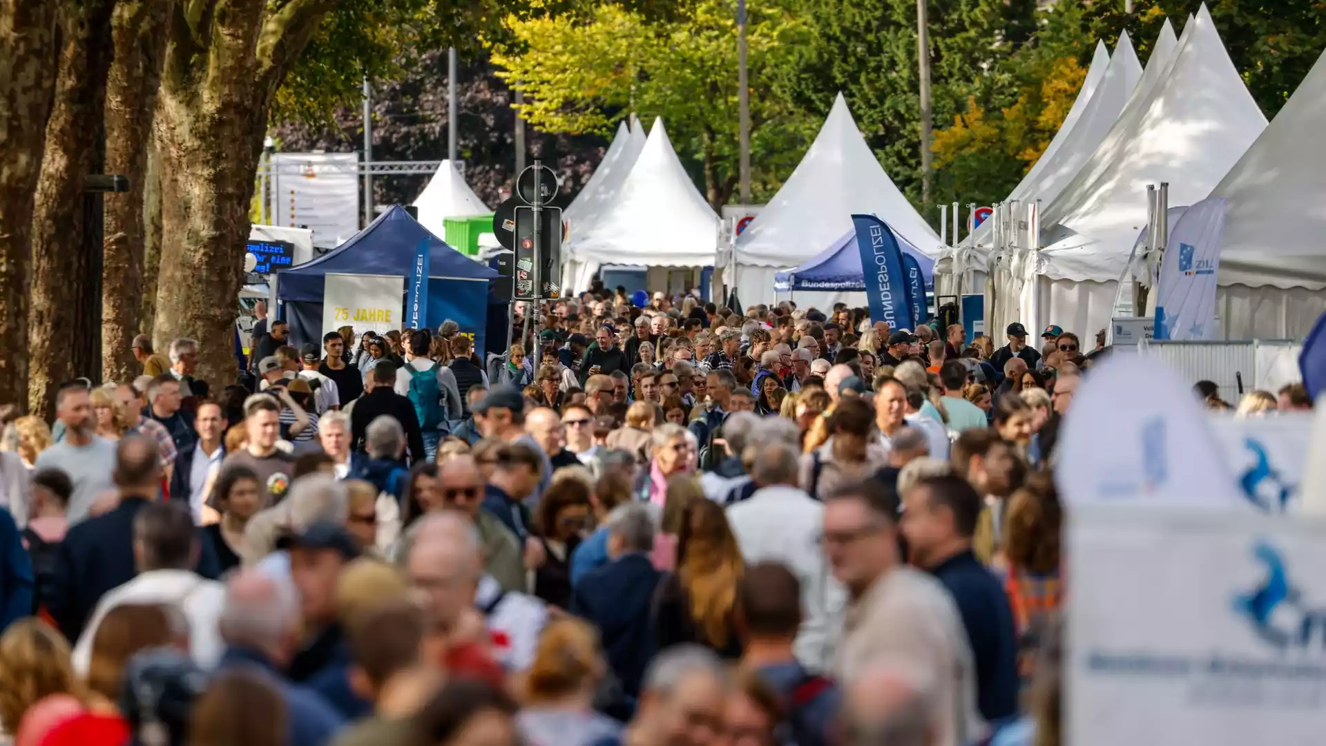 Menschenmenge zwischen Festival- und Informationszelten im Freien