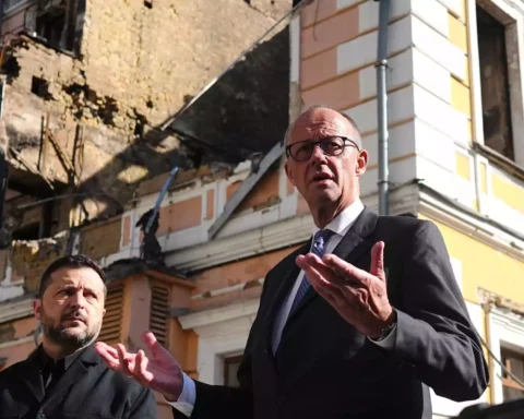 Friedrich Merz spricht vor einem beschädigten Gebäude in Kiew, neben ihm steht Wolodymyr Selenskyj.