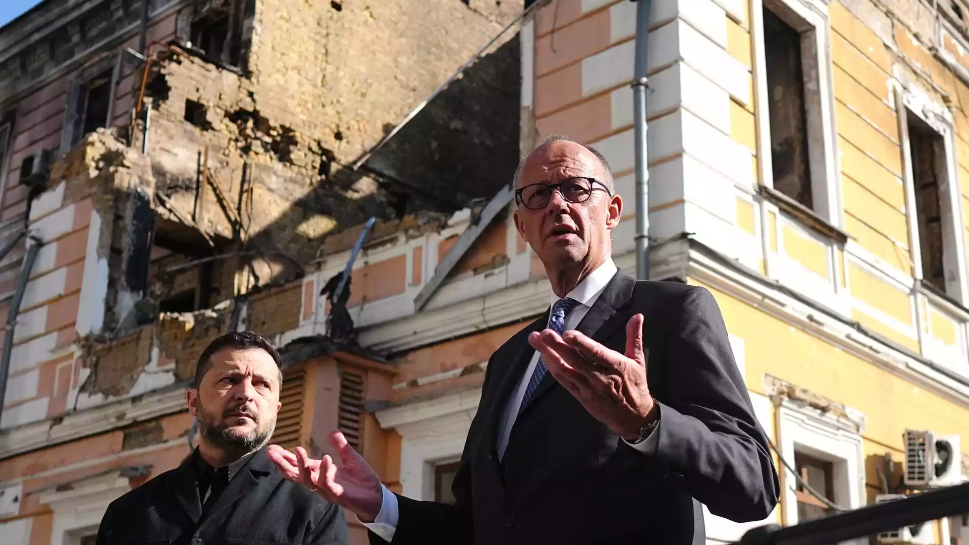 Merz sagt Ukraine weitere Hilfe zu und fordert Putin zum Kriegsende auf 1 Friedrich Merz spricht vor einem beschädigten Gebäude in Kiew, neben ihm steht Wolodymyr Selenskyj.