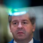 Ein Mann mit grauem Haar blickt ernst in die Kamera.