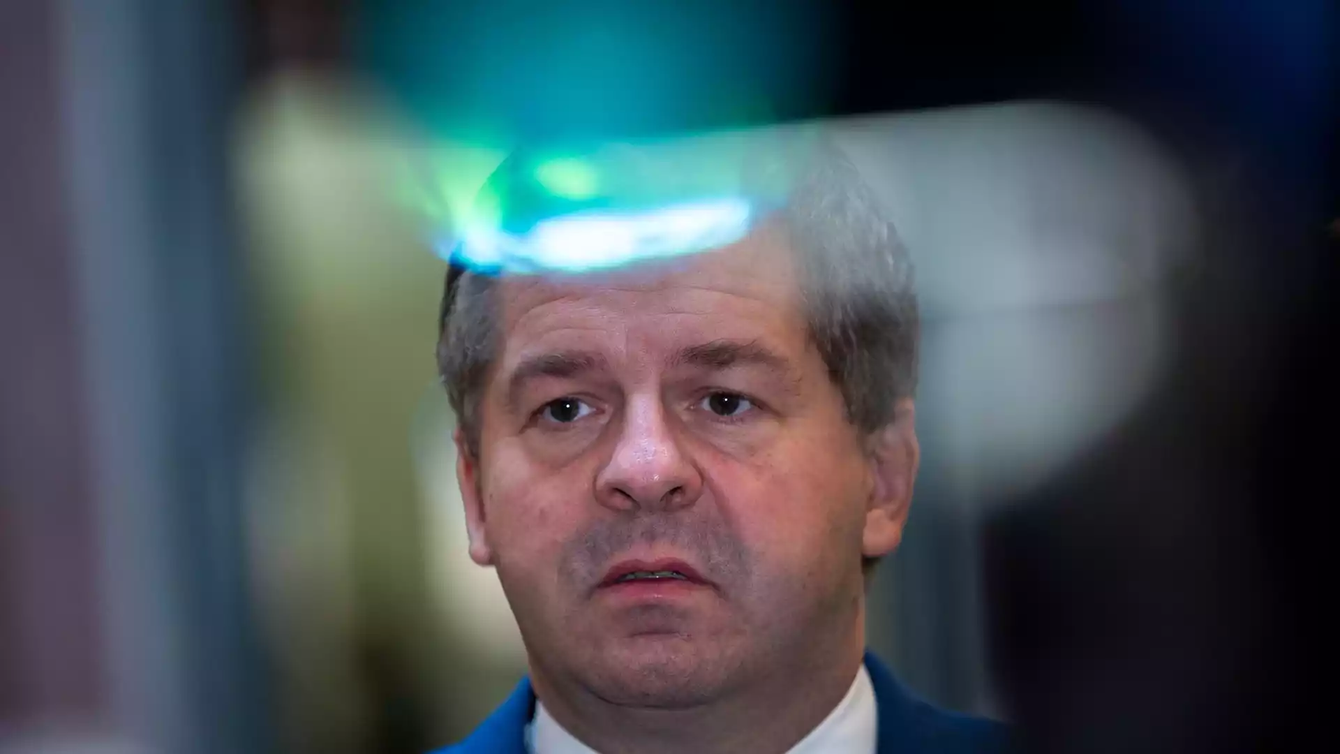 Ein Mann mit grauem Haar blickt ernst in die Kamera.