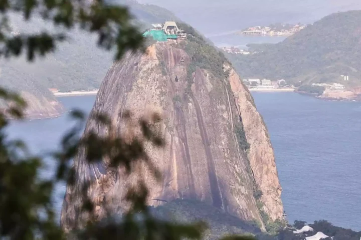 Blick auf den Zuckerhut in Rio de Janeiro mit Meer und Hügeln im Hintergrund.