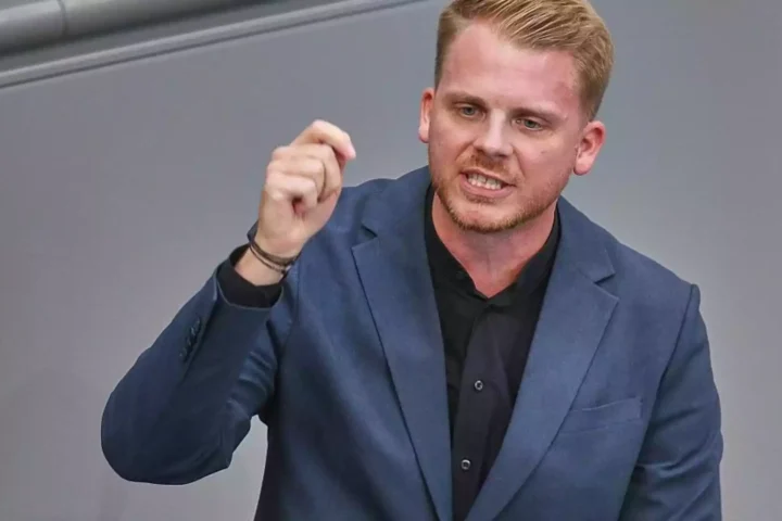 Ein Mann im blauen Anzug spricht und gestikuliert auf einer Bühne.