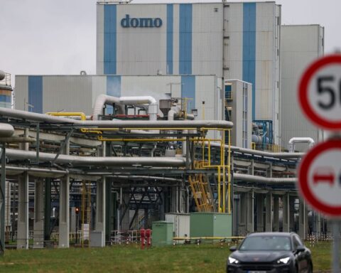 Industrieanlage mit Rohrleitungen und Gebäude mit der Aufschrift „domo“, davor Verkehrsschilder und ein Auto.