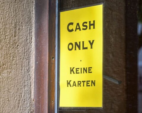 Gelbes Schild an einer Tür mit der Aufschrift „Cash only“ und „Keine Karten“.