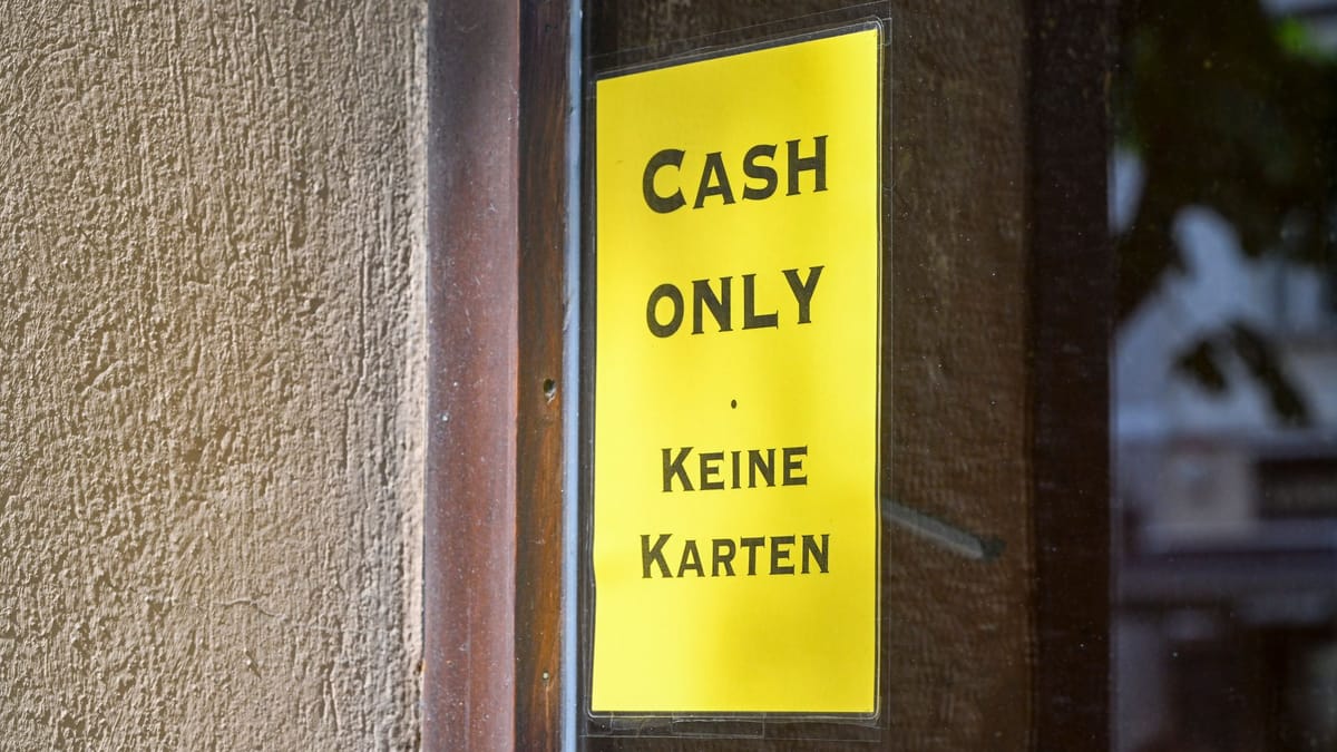 Gelbes Schild an einer Tür mit der Aufschrift „Cash only“ und „Keine Karten“.