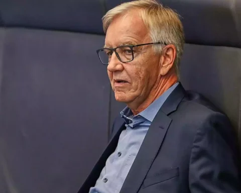 Dietmar Bartsch steht mit Brille und dunkelblauem Sakko vor einem grauen Hintergrund.