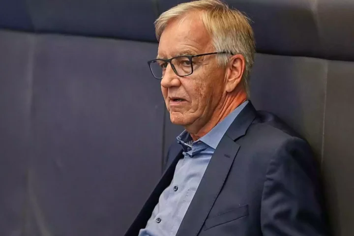 Dietmar Bartsch steht mit Brille und dunkelblauem Sakko vor einem grauen Hintergrund.