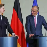 Zwei Politiker stehen an Rednerpulten vor EU-, Deutschland- und Litauen-Flaggen.