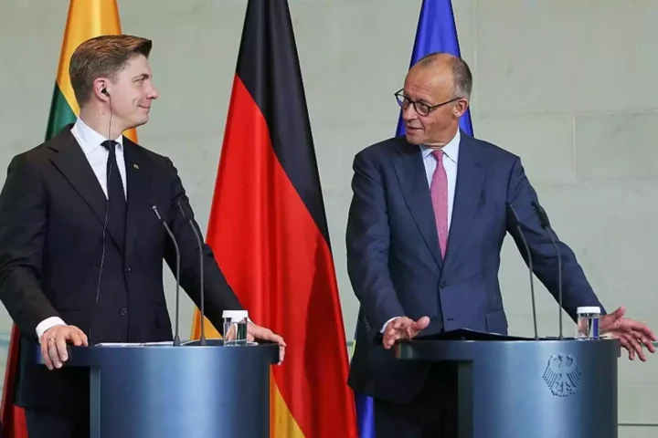 Zwei Politiker stehen an Rednerpulten vor EU-, Deutschland- und Litauen-Flaggen.