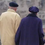 Zwei ältere Menschen stehen mit dem Rücken zur Kamera im Freien.