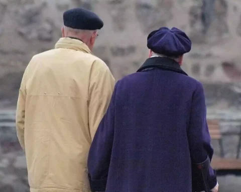 Zwei ältere Menschen stehen mit dem Rücken zur Kamera im Freien.