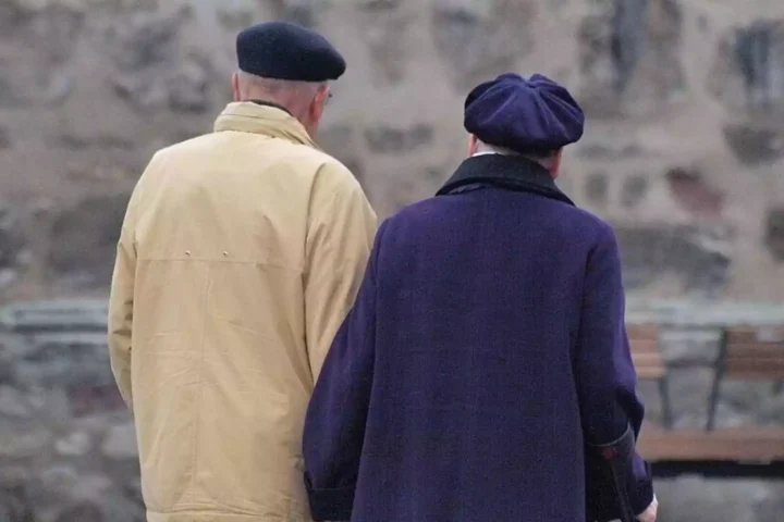 Zwei ältere Menschen stehen mit dem Rücken zur Kamera im Freien.
