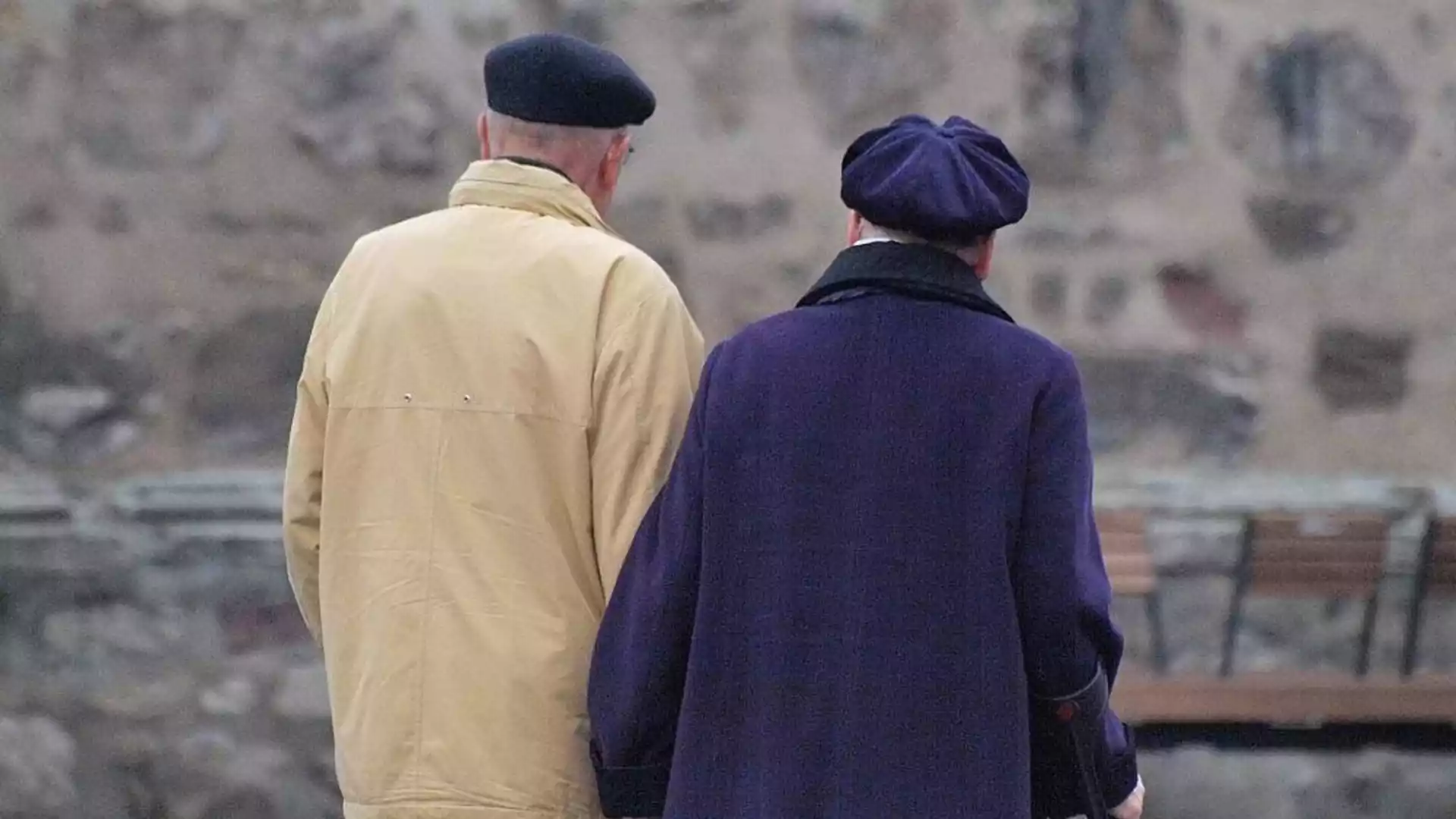 Zwei ältere Menschen stehen mit dem Rücken zur Kamera im Freien.