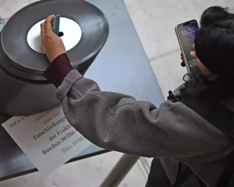Eine Person fotografiert eine Abstimmungsanzeige an einer Installation mit einem Smartphone.