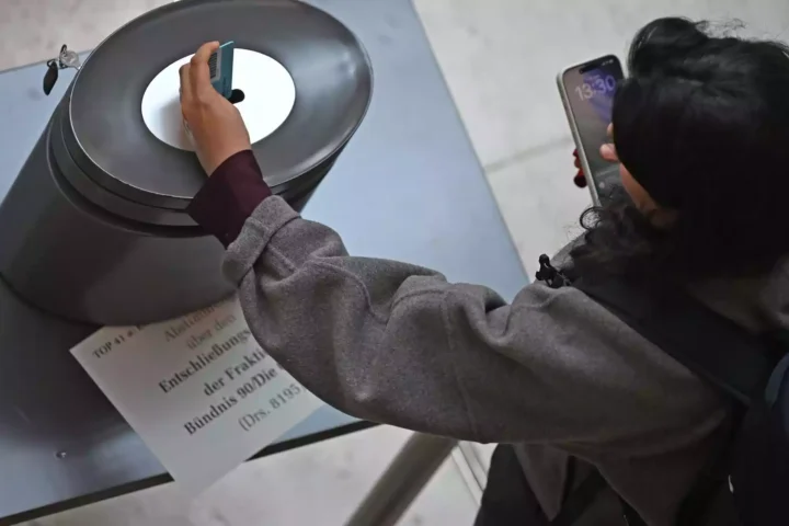 Eine Person fotografiert eine Abstimmungsanzeige an einer Installation mit einem Smartphone.