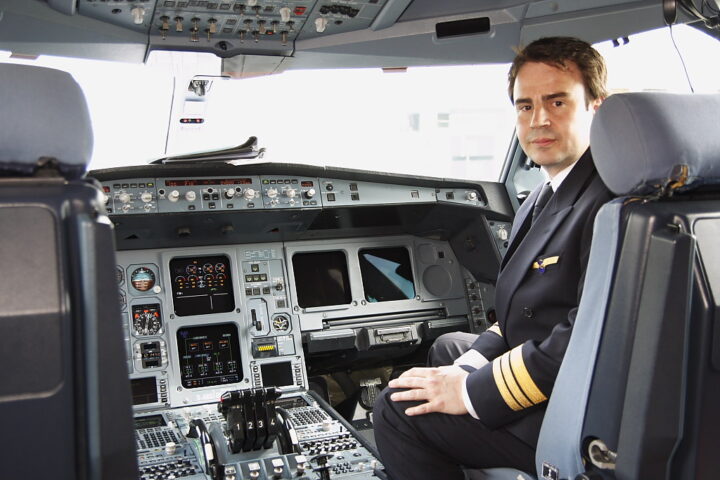 Ein Pilot sitzt im Cockpit eines Verkehrsflugzeugs.