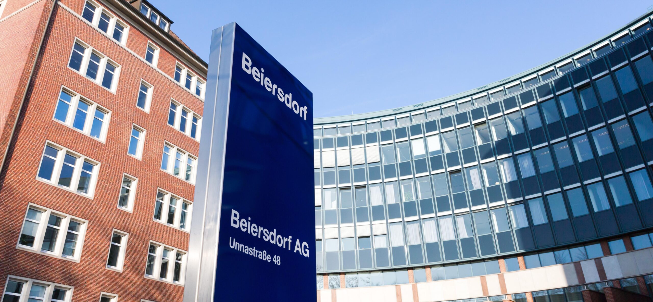 Beiersdorf-Standort mit Firmenschild vor Bürogebäuden.