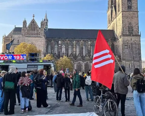 Menschen demonstrieren vor dem Magdeburger Dom, im Vordergrund eine rote Fahne.