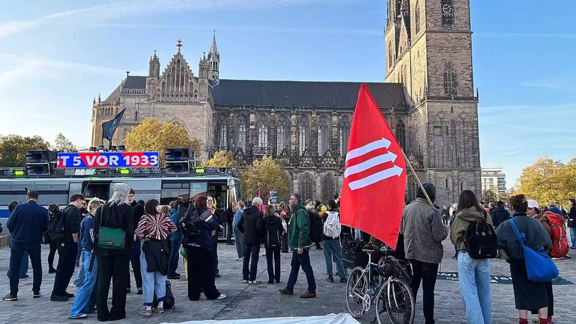 Proteste begleiten AfD-Kandidatur für Landtagspräsidenten in Sachsen-Anhalt 1 Menschen demonstrieren vor dem Magdeburger Dom, im Vordergrund eine rote Fahne.