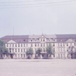Historisches Parlaments- oder Regierungsgebäude mit langer Fassade und Bäumen davor.