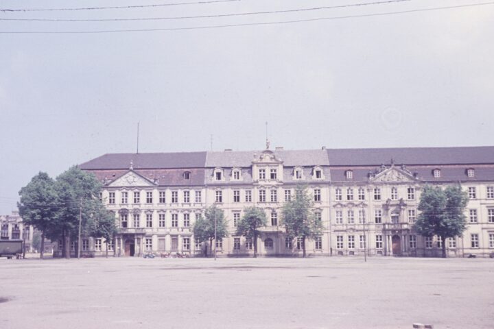 Historisches Parlaments- oder Regierungsgebäude mit langer Fassade und Bäumen davor.