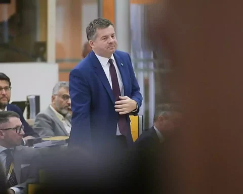 Tobias Rausch steht in einem Plenarsaal und spricht vor mehreren Abgeordneten.