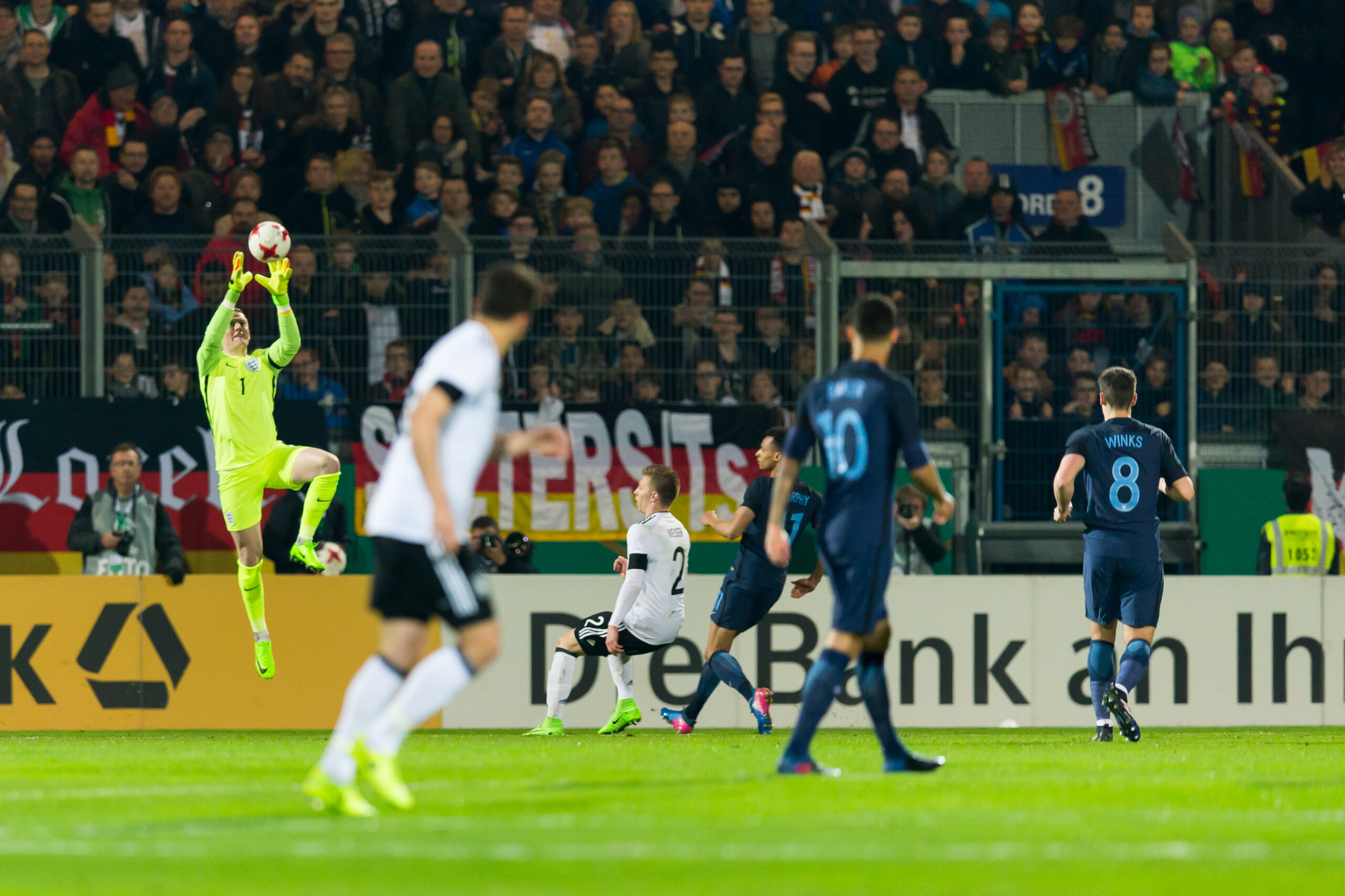 Bundesliga-Präsidium fordert weitere Gespräche zur 50+1-Regel 1 Torwart in neongelbem Trikot fängt einen Ball im Strafraum vor Zuschauern im Stadion.