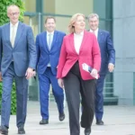 Mehrere Politiker gehen vor einem Regierungsgebäude aufeinander zu.