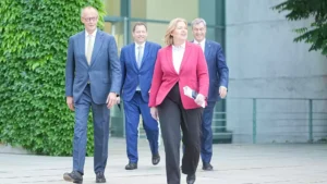 Mehrere Politiker gehen vor einem Regierungsgebäude aufeinander zu.