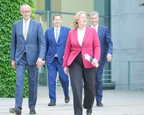 Mehrere Politiker gehen vor einem Regierungsgebäude aufeinander zu.