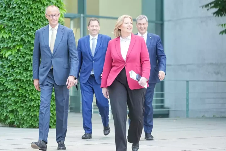 Mehrere Politiker gehen vor einem Regierungsgebäude aufeinander zu.