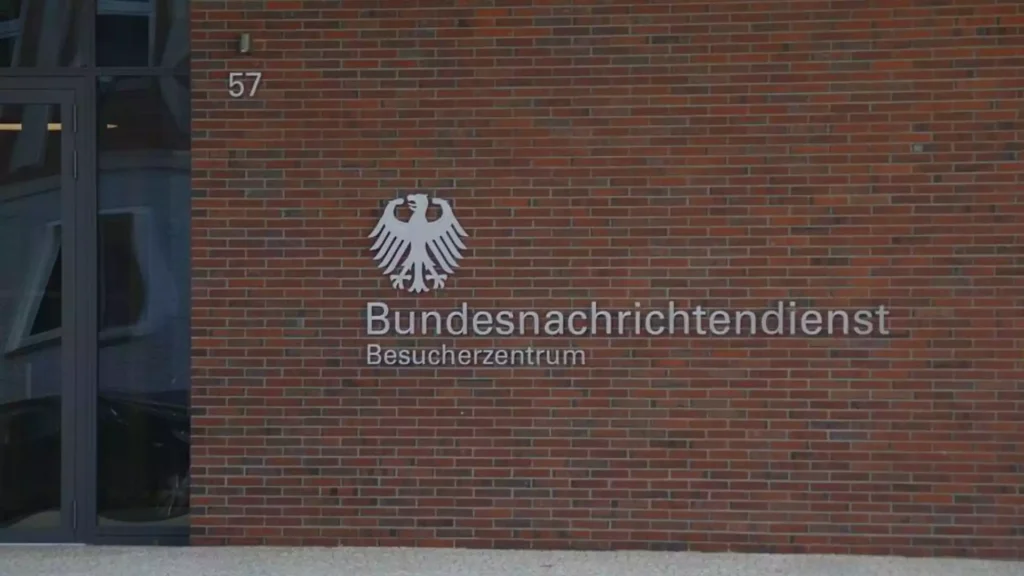 Außenansicht des Besucherzentrums des Bundesnachrichtendienstes mit Adler-Emblem und Schriftzug an einer Backsteinwand.